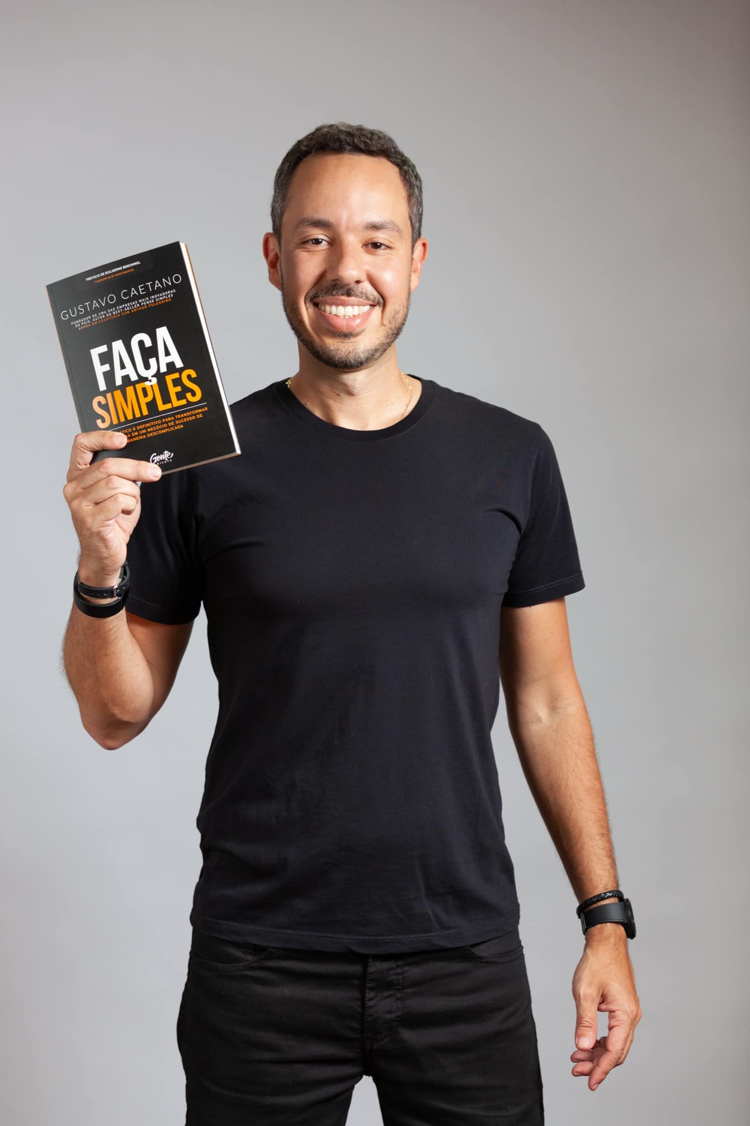 Gustavo Caetano olhando para o livro Pense Simples