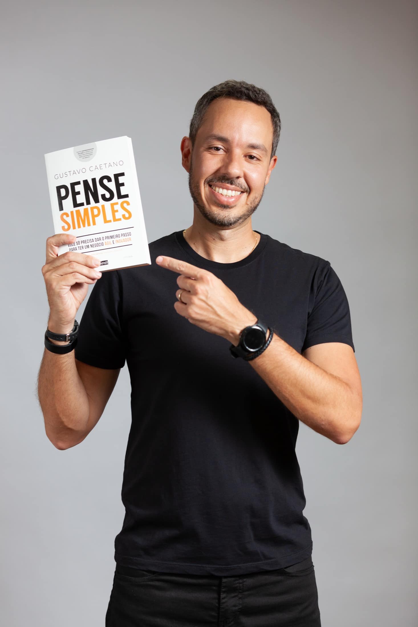 Gustavo Caetano sorrindo com o livro Pense Simples